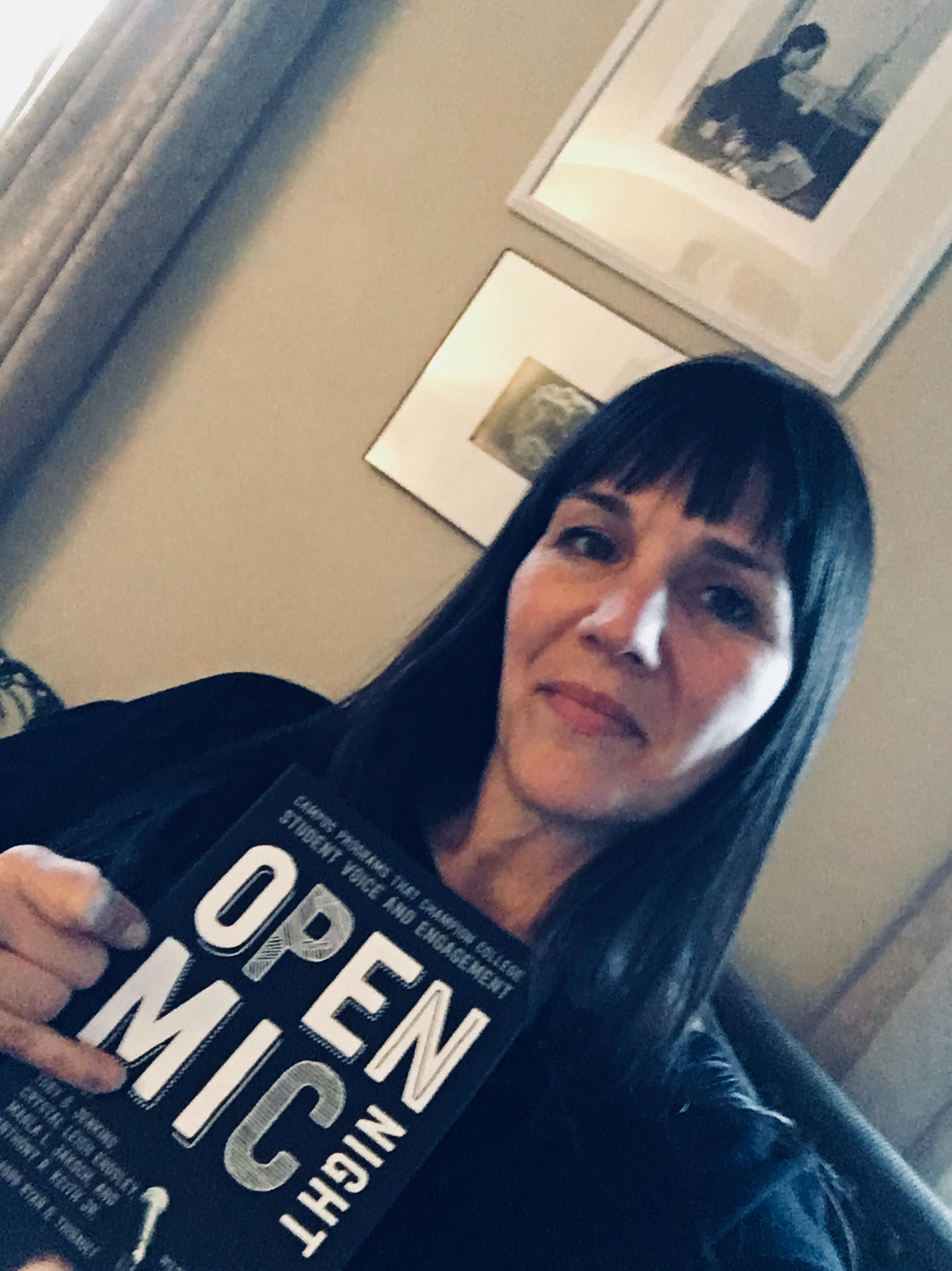 selfie of woman holding open mic night flyer